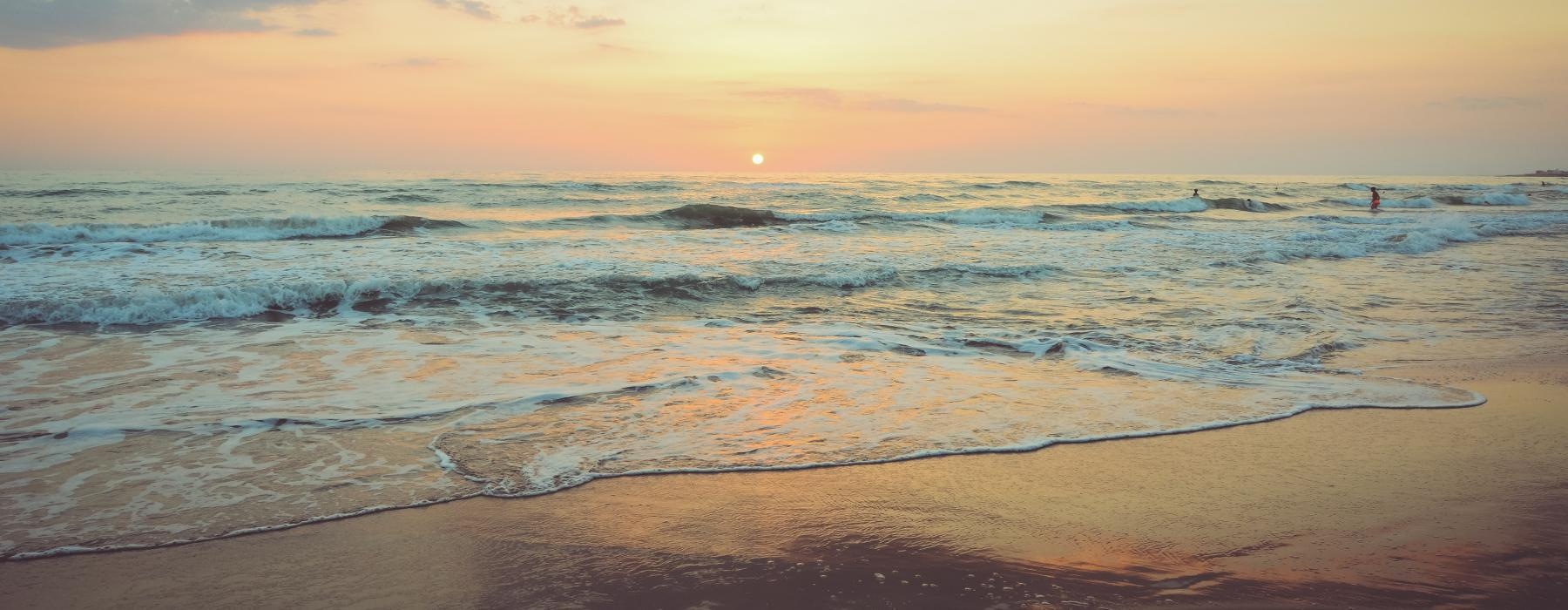 a beach with waves and a sunset